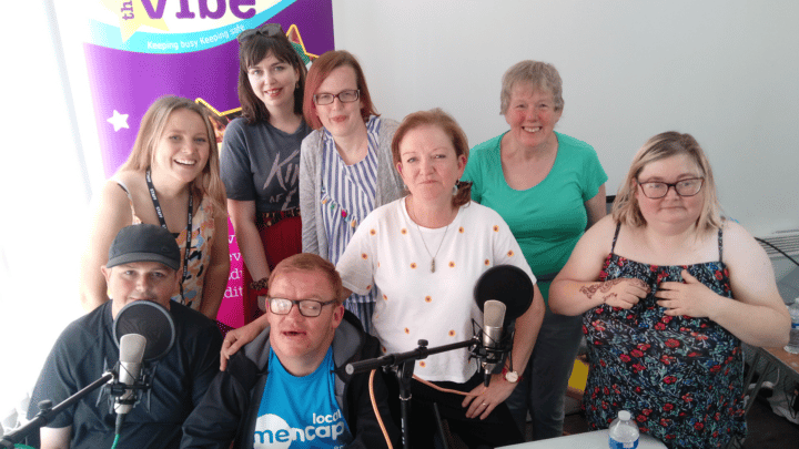A diverse group from Kensington Vision smiling at the camera in front of a branded pull up banner