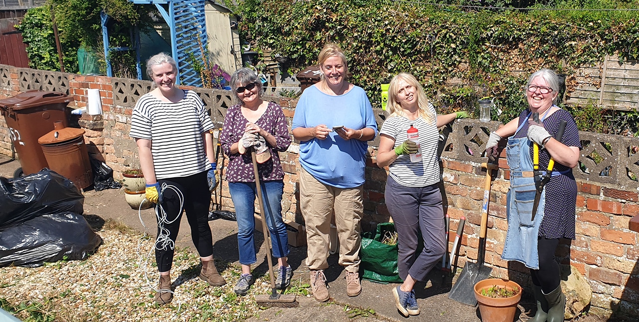 Five women outside taking a break from gardening