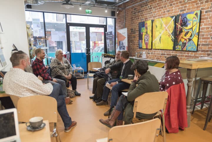 A mixed group of people meeting and talking in DC1 cafe and art gallery.
