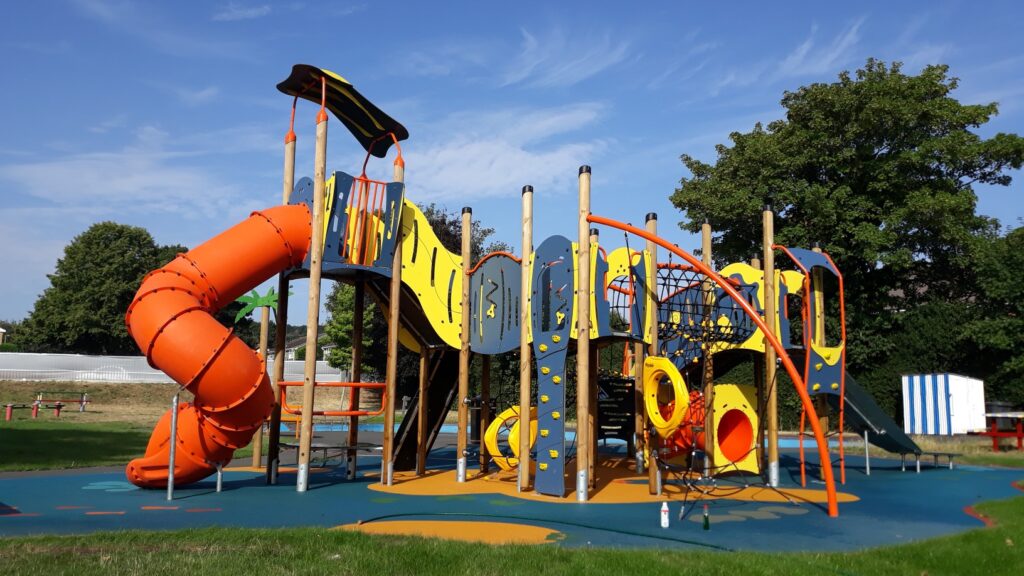 Children's colourful play area with orange slide in local park.