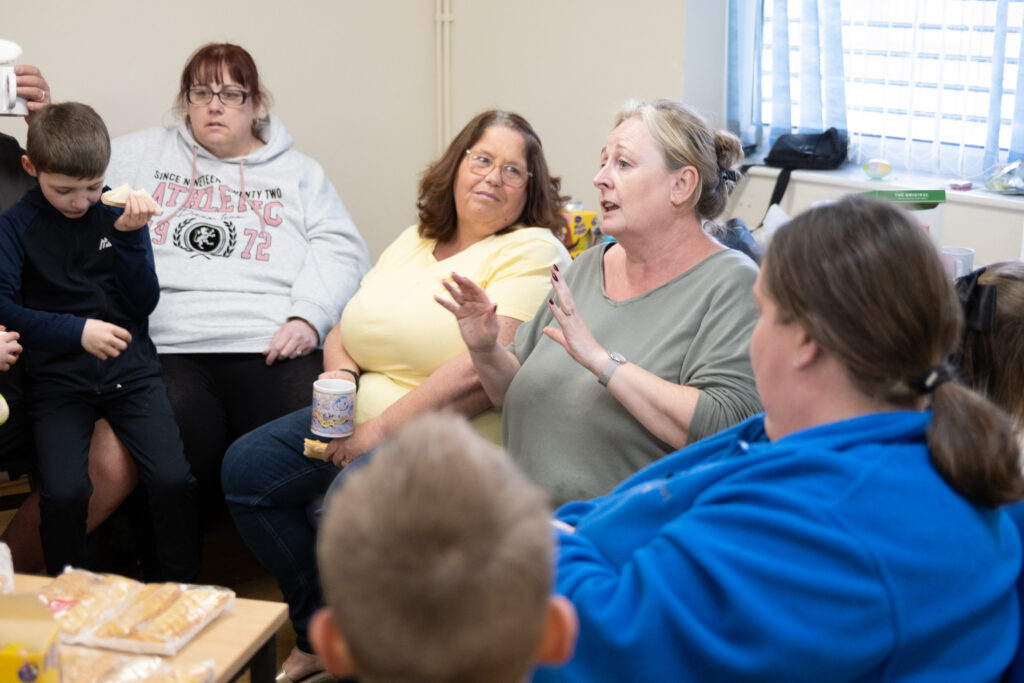 A group of five adults sit in a circle talking