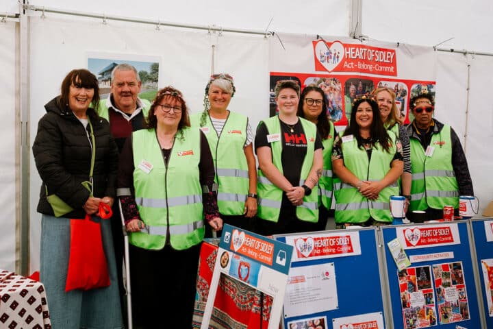 Group photo of volunteers wearing bright green high-vis vests standing inside a white tent.